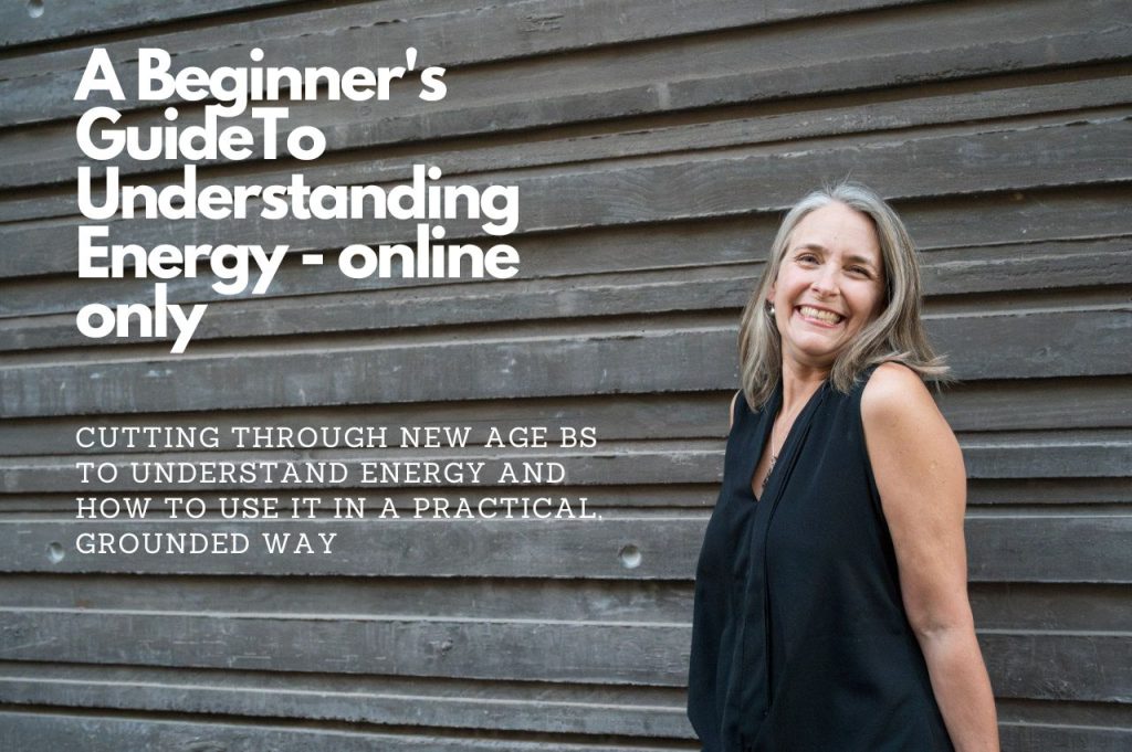 Picture of Lisa Higgins wearing a black shirt, standing against a wooden wall. Text on the photo says, A Beginner’s Guide To Understanding - online only, cutting through new age BS to understand energy and how to use it in a practical grounded way